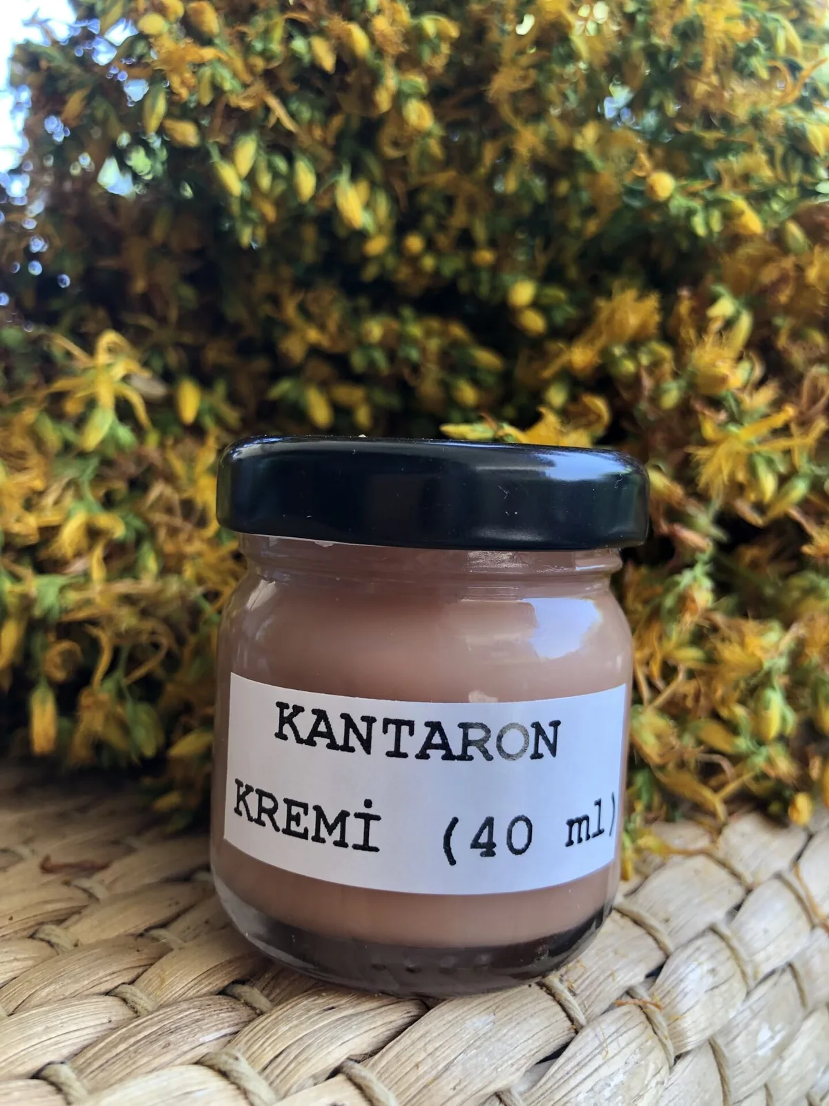 Sarı kantaron çiçeklerinin önünde cam kavanozda kantaron kremi